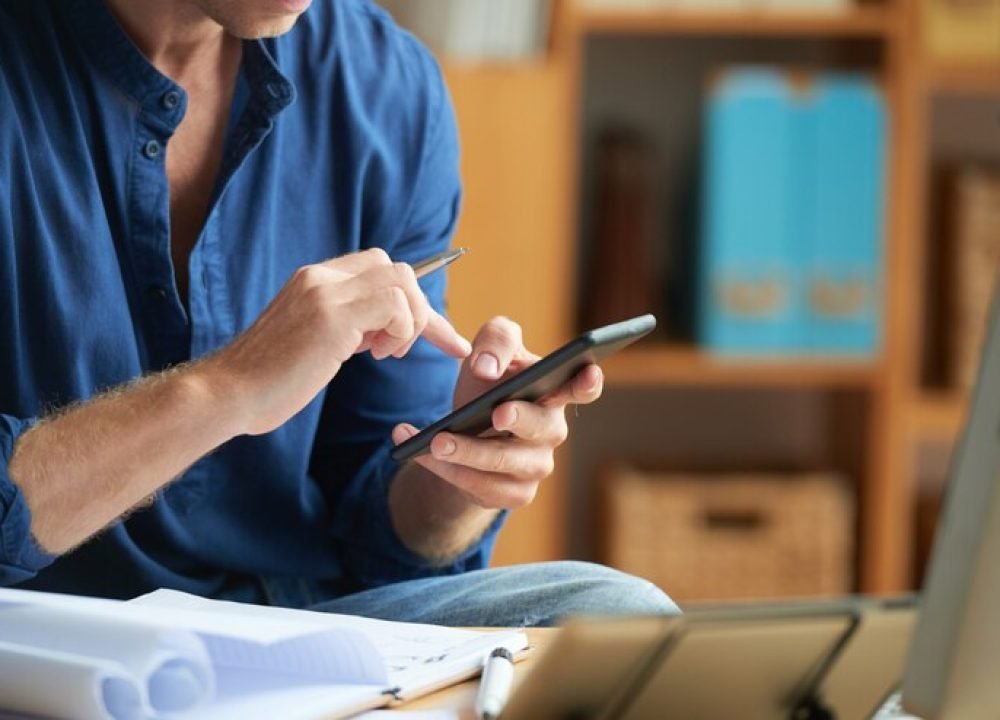 casually-dressed-unrecognizable-man-using-smartphone-work-office_1098-20449 (1)